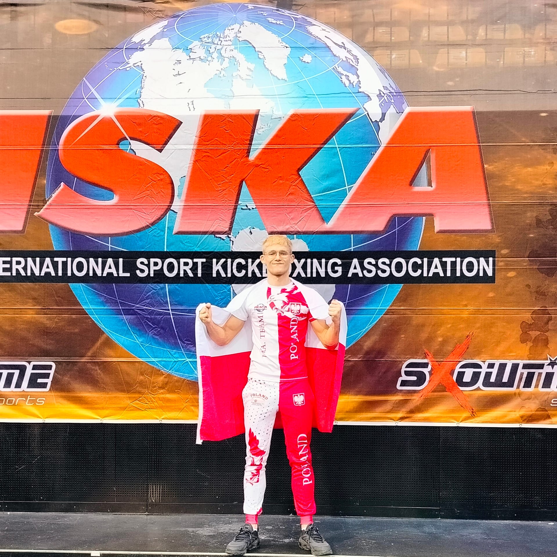 Sebastian pozuje do zdjęcia na tle ISKA w której brał udział Sebastian pozuje do zdjęcia na tle ISKA